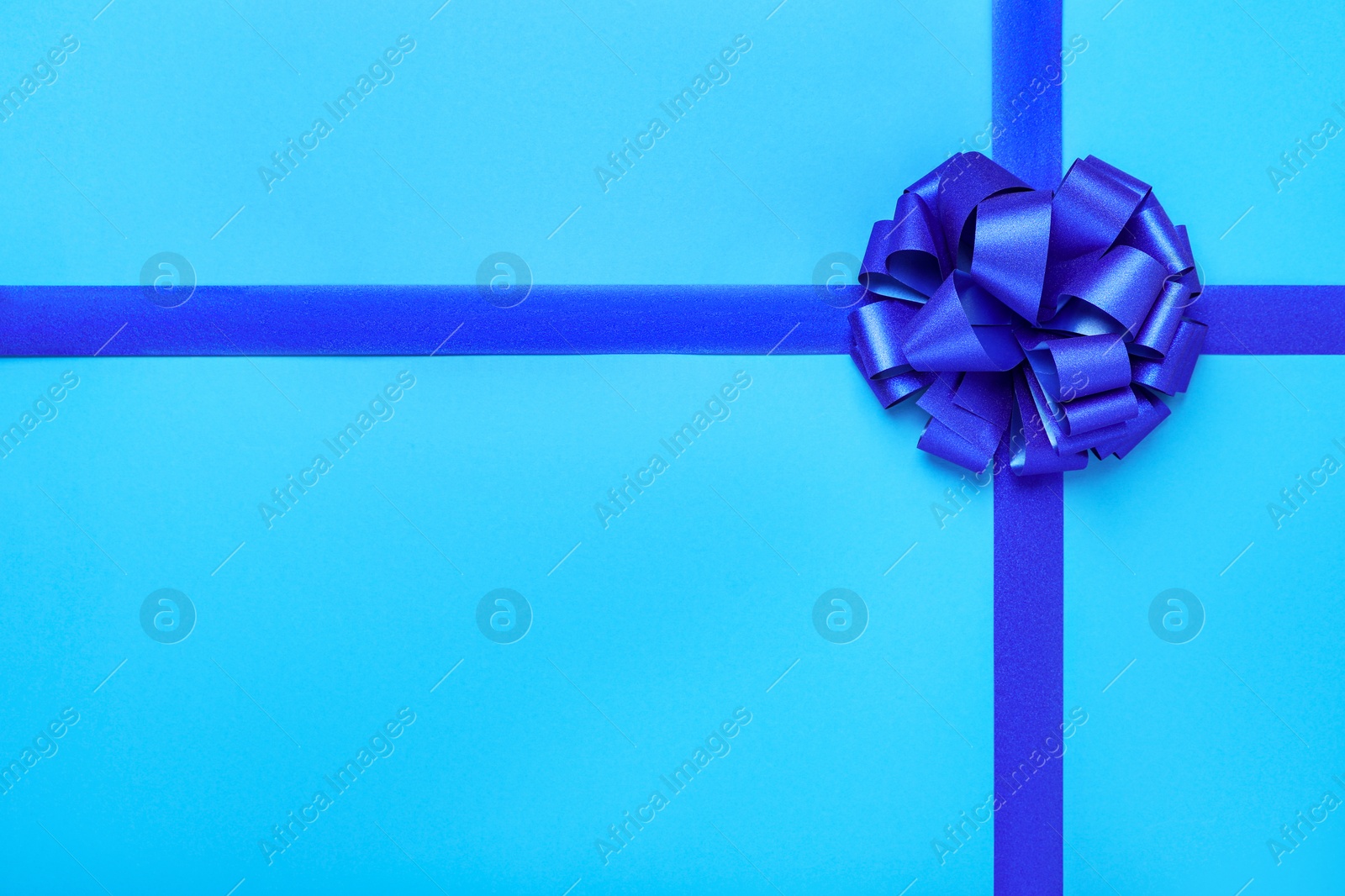 Photo of Ribbons with bow on light blue background, top view. Space for text