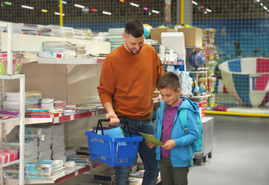 Little boy and father choosing school stationery in store