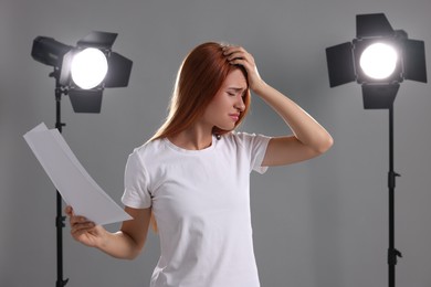 Photo of Casting call. Emotional woman with script performing on grey background