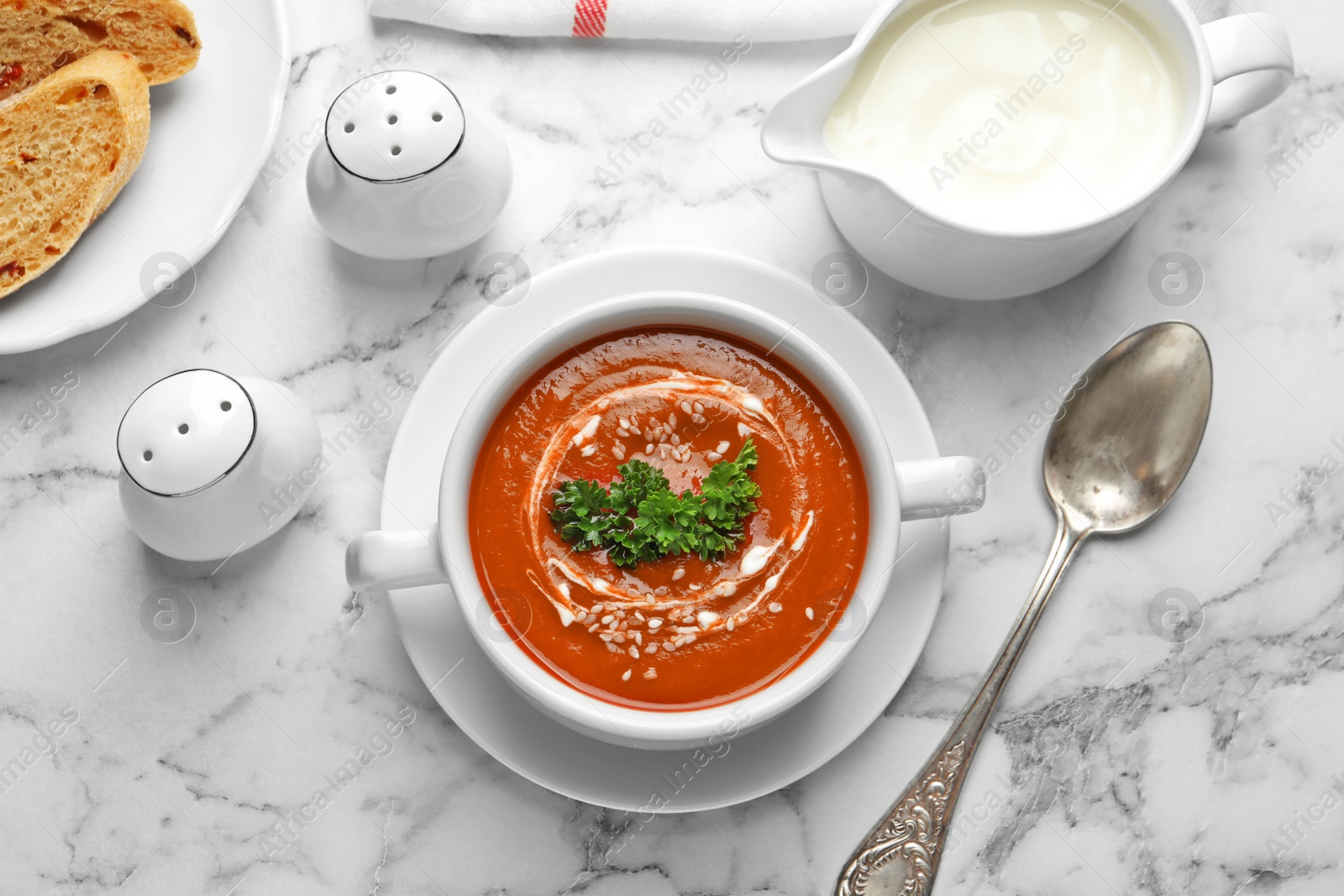 Photo of Dish with fresh homemade tomato soup on marble table, top view