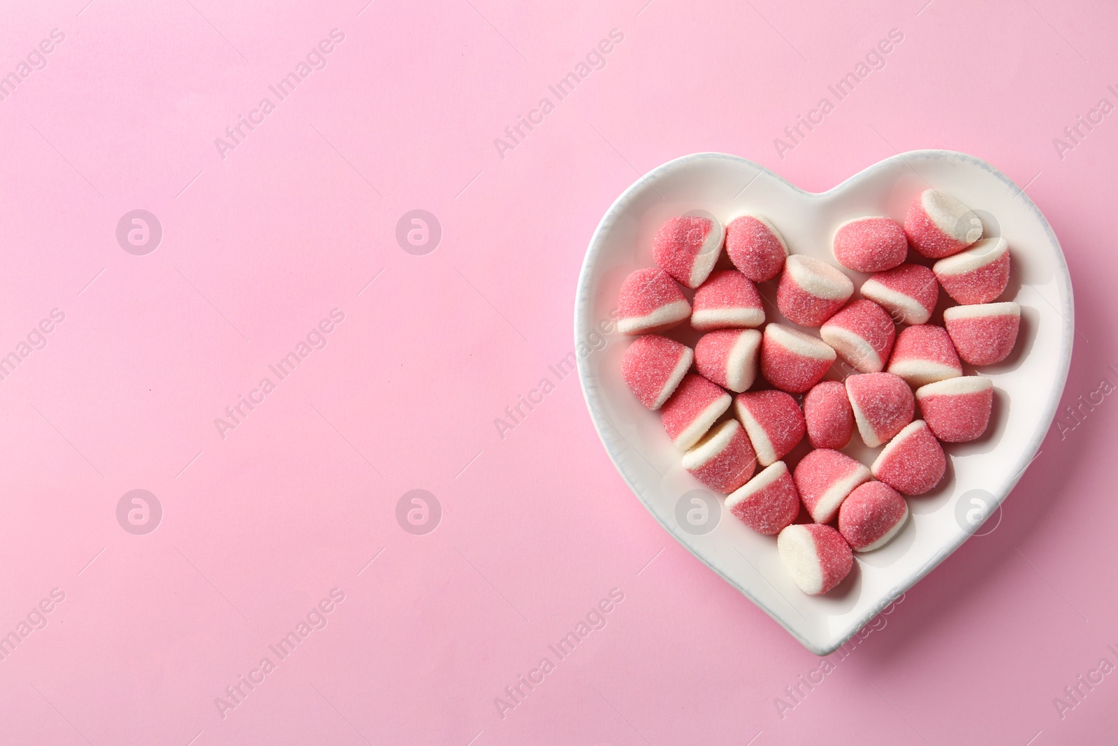 Photo of Plate of sweet jelly candies on pink background, top view. Space for text