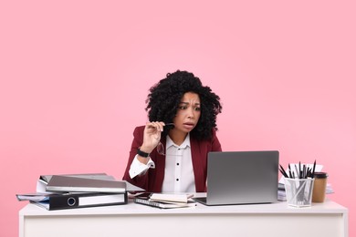 Photo of Stressful deadline. Scared woman looking at laptop at white desk on pink background