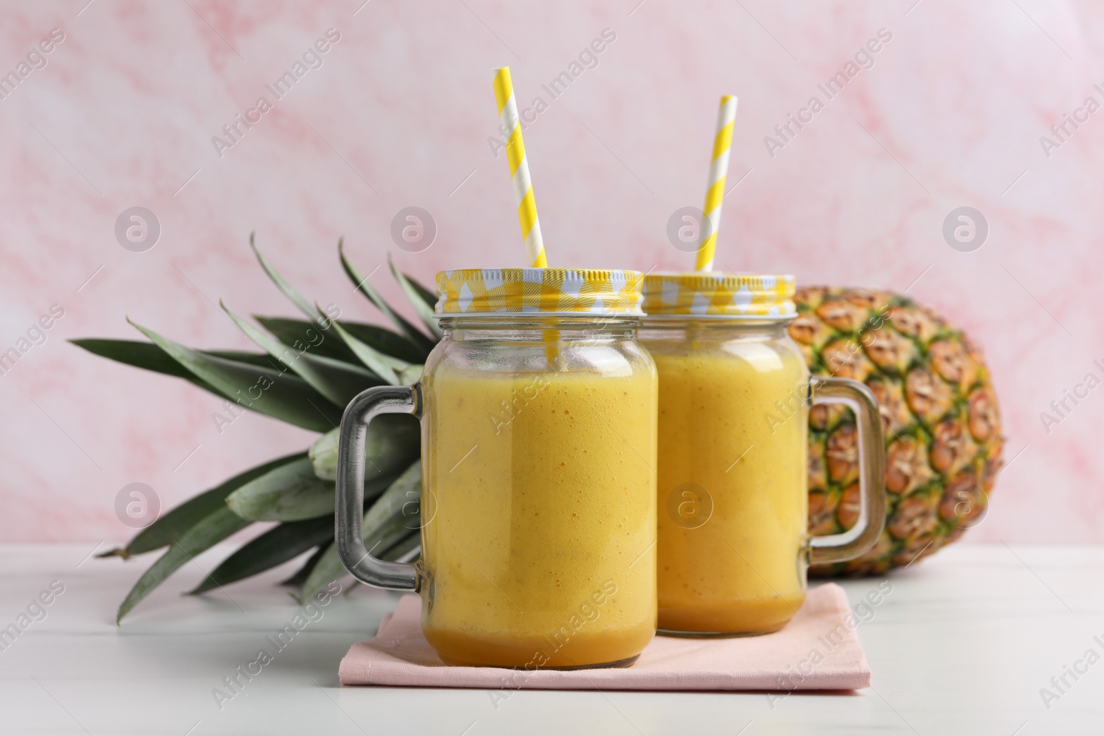 Photo of Tasty pineapple smoothie and fruit on white table