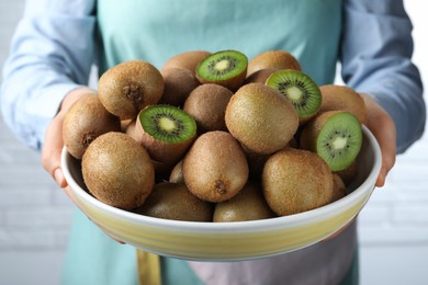 Photo of Woman holding bowl with fresh ripe kiwis on white background, closeup