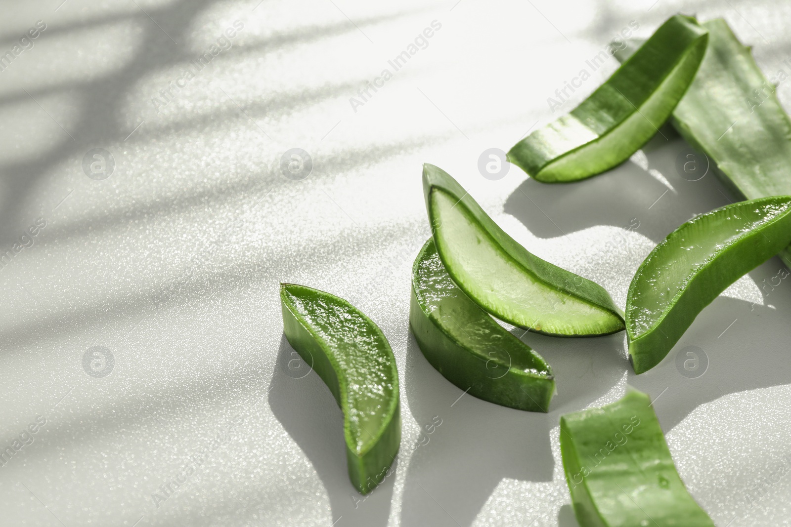 Photo of Fresh aloe vera pieces on white table, closeup. Space for text
