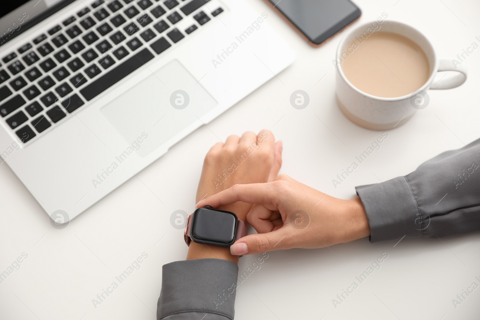 Image of Woman checking stylish smart watch at table, closeup