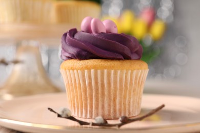 Photo of Tasty Easter cupcake and willow branch on table, closeup