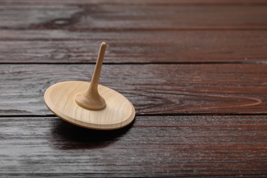 Photo of One spinning top on wooden table, closeup. Space for text