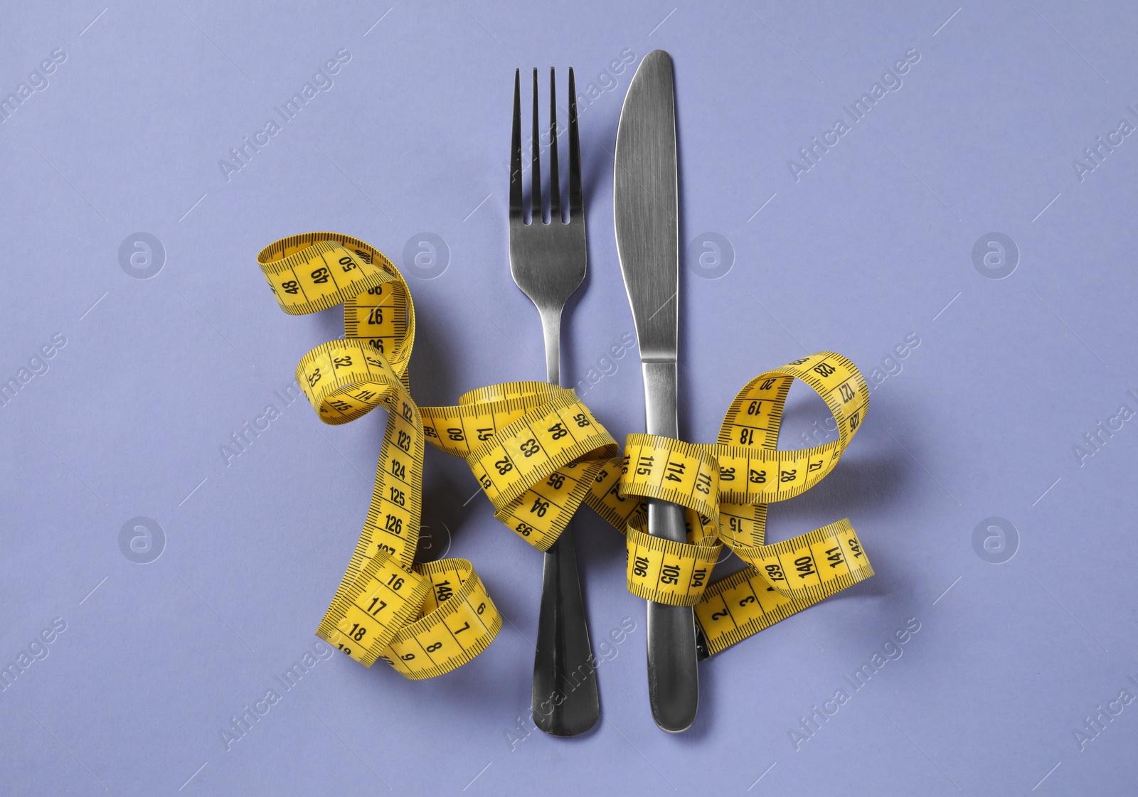 Photo of Cutlery with measuring tape on light purple background, flat lay. Diet concept