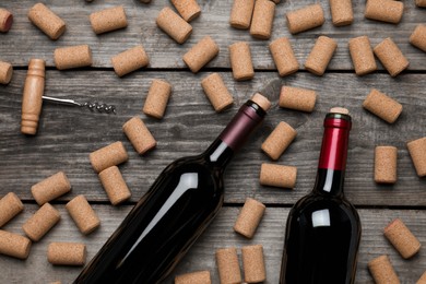 Photo of Wine corks, bottles and corkscrew on wooden table, flat lay