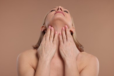 Photo of Beautiful woman touching her neck on beige background