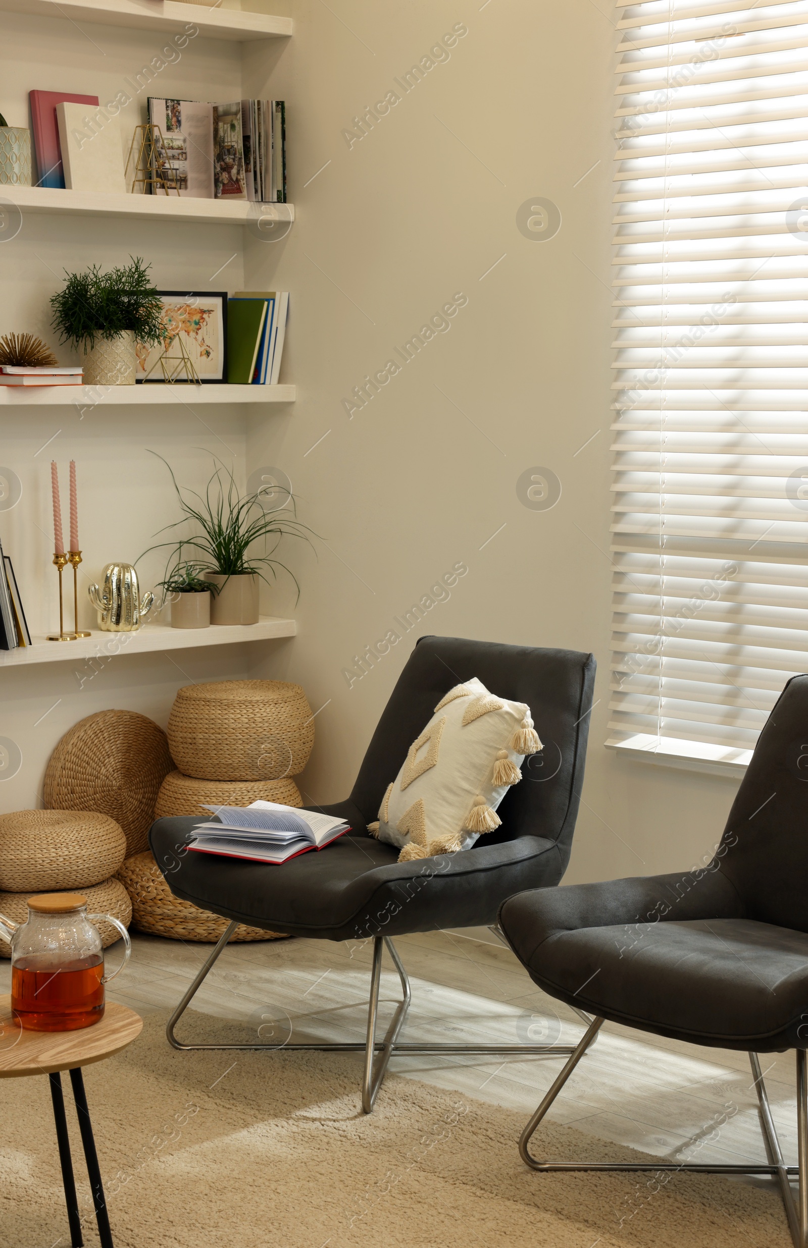 Photo of Comfortable chairs near shelves with different decor in room. Interior design