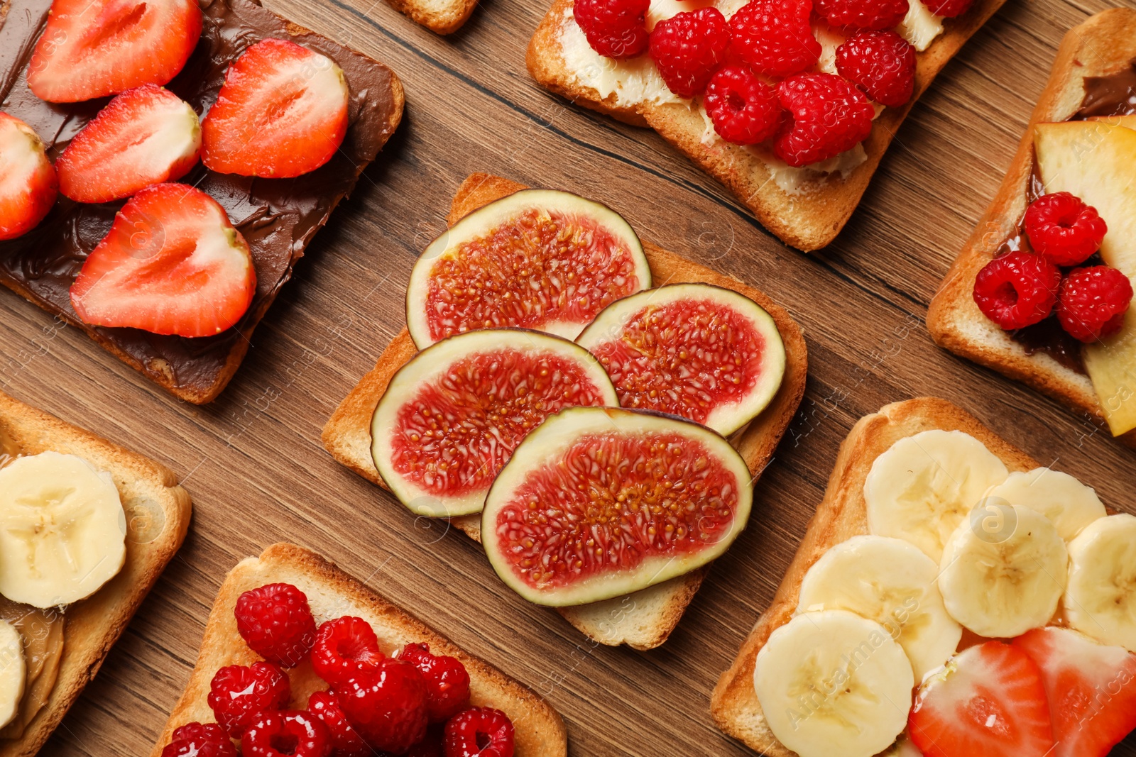 Photo of Tasty toasts with different spreads and fruits on wooden table, flat lay