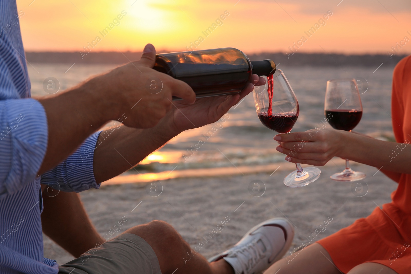 Photo of Lovely couple having picnic near river at sunset, closeup