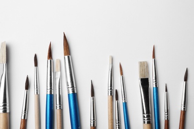 Photo of Different paint brushes on white background, top view