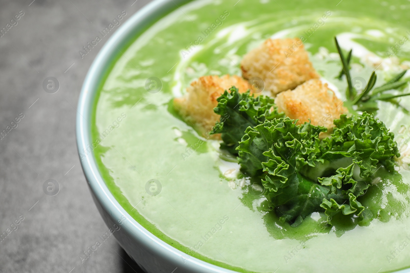 Photo of Tasty kale soup with croutons on grey table, closeup