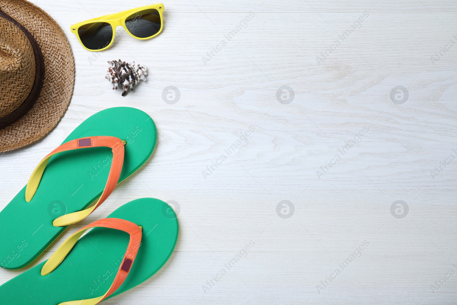 Photo of Stylish flip flops, sunglasses and hat on white wooden background, flat lay. Space for text