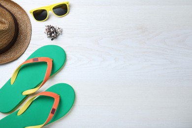 Photo of Stylish flip flops, sunglasses and hat on white wooden background, flat lay. Space for text