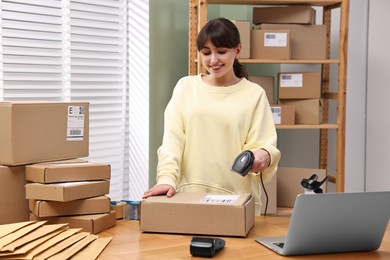 Photo of Parcel packing. Post office worker with scanner reading barcode indoors