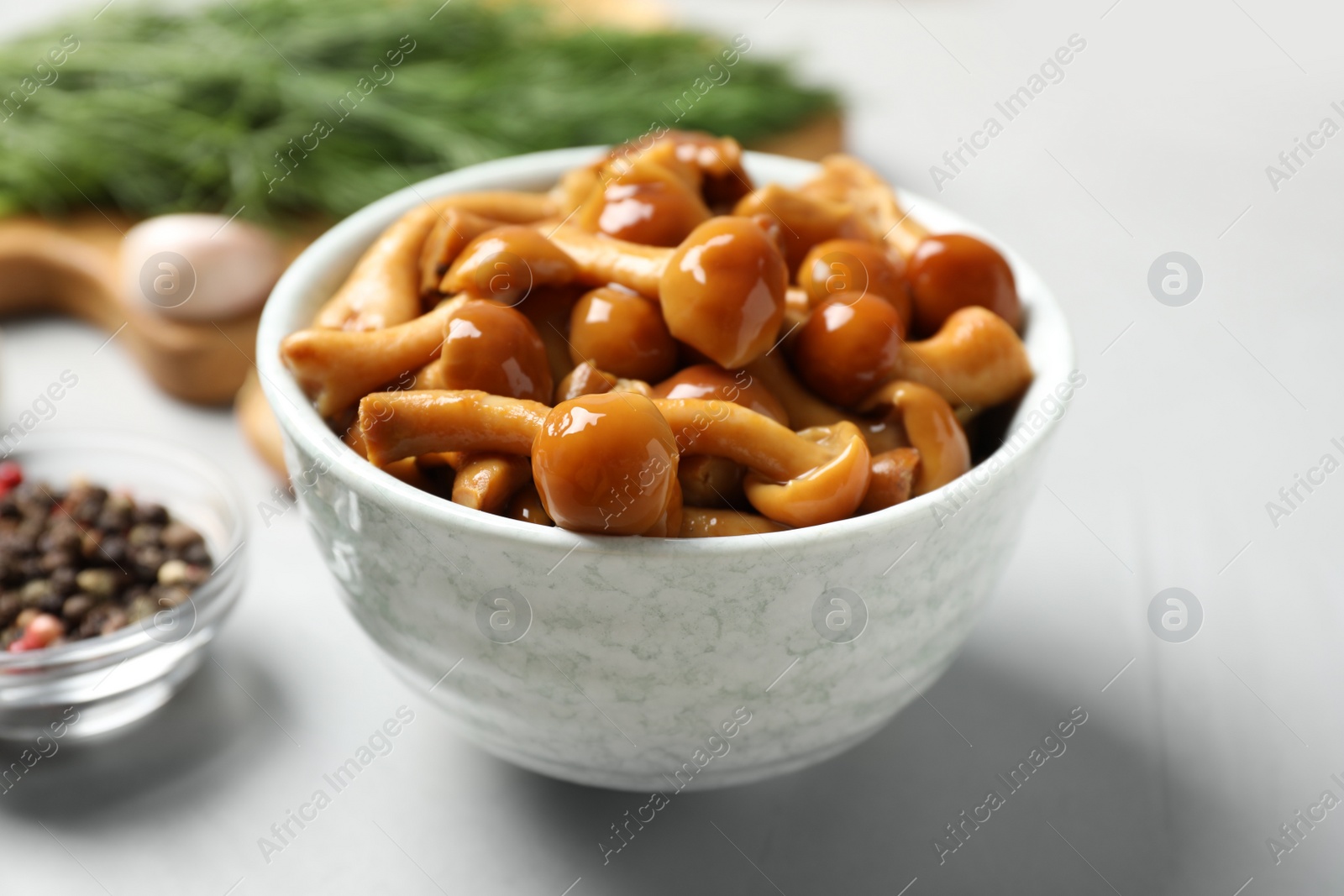 Photo of Tasty marinated mushrooms in bowl on grey table, closeup