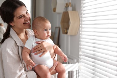 Photo of Happy young mother with her baby near window at home. Space for text