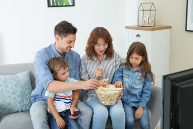 Photo of Family watching TV with popcorn in room