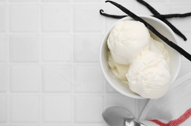 Photo of Delicious ice cream, spoon and vanilla pods on white tiled table, flat lay. Space for text