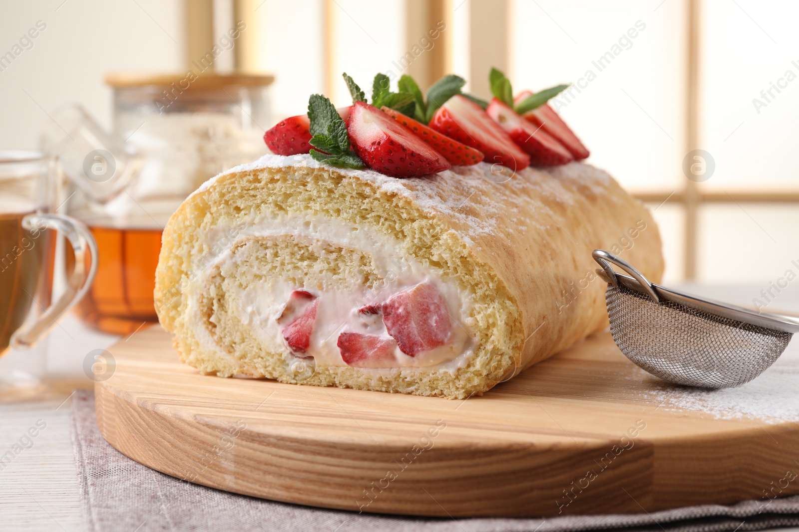 Photo of Delicious cake roll with strawberries and cream on table indoors