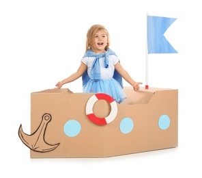 Photo of Cute little girl playing with cardboard ship on white background