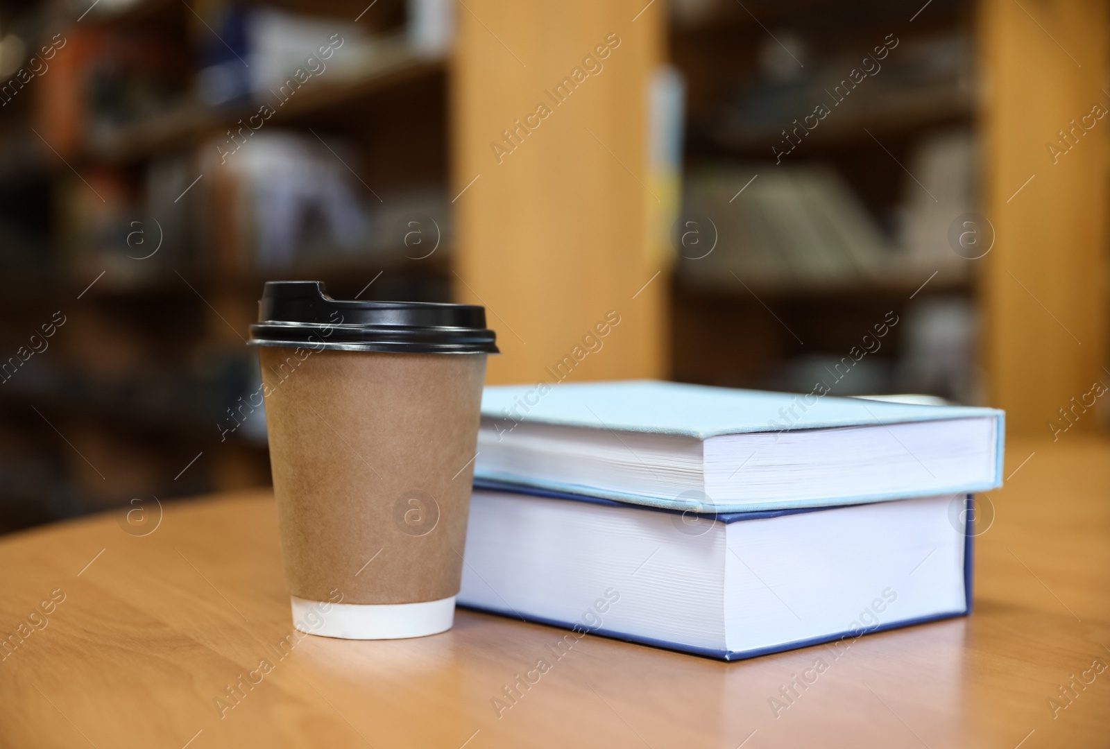 Photo of Books and cup of coffee on table in library
