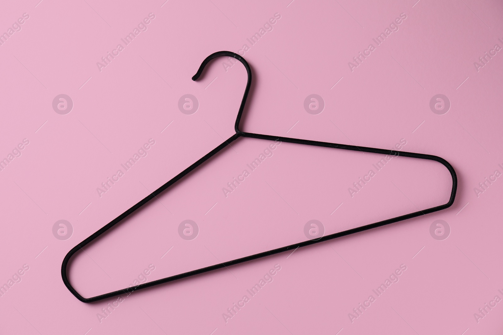 Photo of One black hanger on pink background, top view