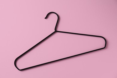 Photo of One black hanger on pink background, top view