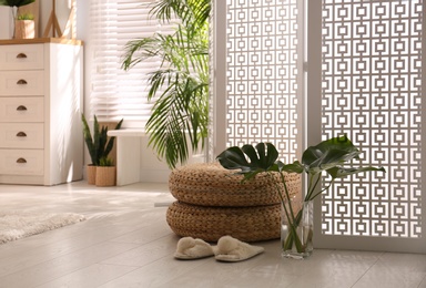 Stylish room interior with white folding screen and plants