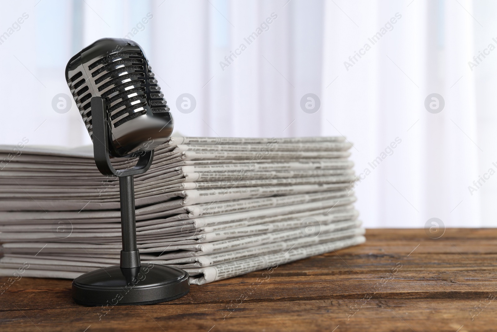 Photo of Newspapers and vintage microphone on wooden table. Journalist's work