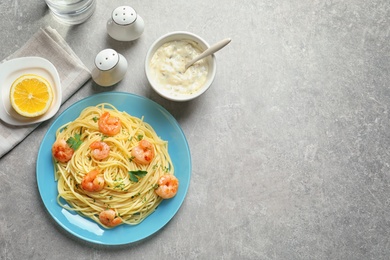 Plate with spaghetti and shrimps on grey background, top view