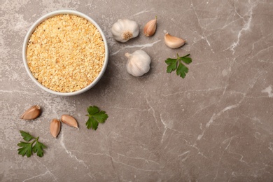 Photo of Bulbs, cloves, parsley and bowl with granulated dried garlic on table, top view