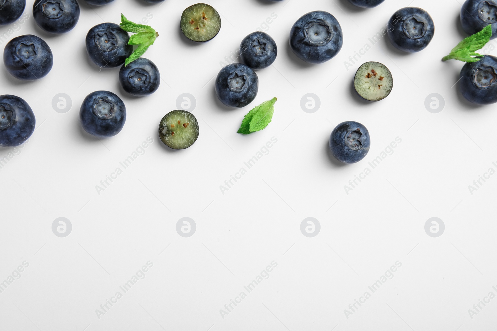 Photo of Tasty ripe blueberries and leaves on white background, flat lay