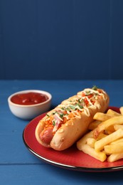 Photo of Delicious hot dog with bacon, carrot and parsley on blue wooden table