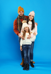 Happy family in warm clothes on blue background. Winter vacation