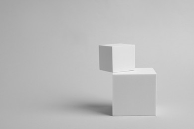 Photo of Scene with podium for product presentation. Cubes on light grey background, space for text