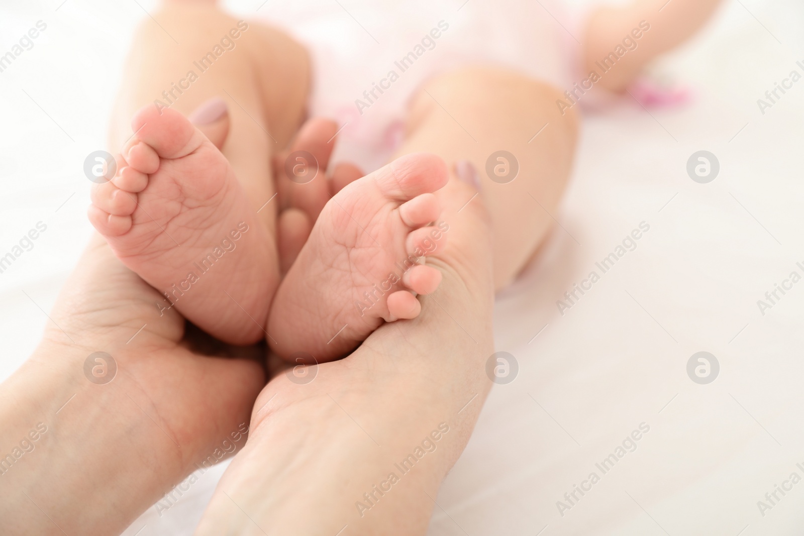Photo of Mother holding her baby's feet on bed, closeup