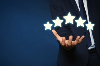 Image of Man showing icons of five stars on blue background, closeup. Quality rating