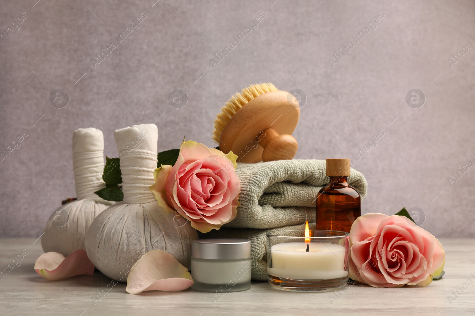 Photo of Composition with spa products, roses and candle on grey wooden table