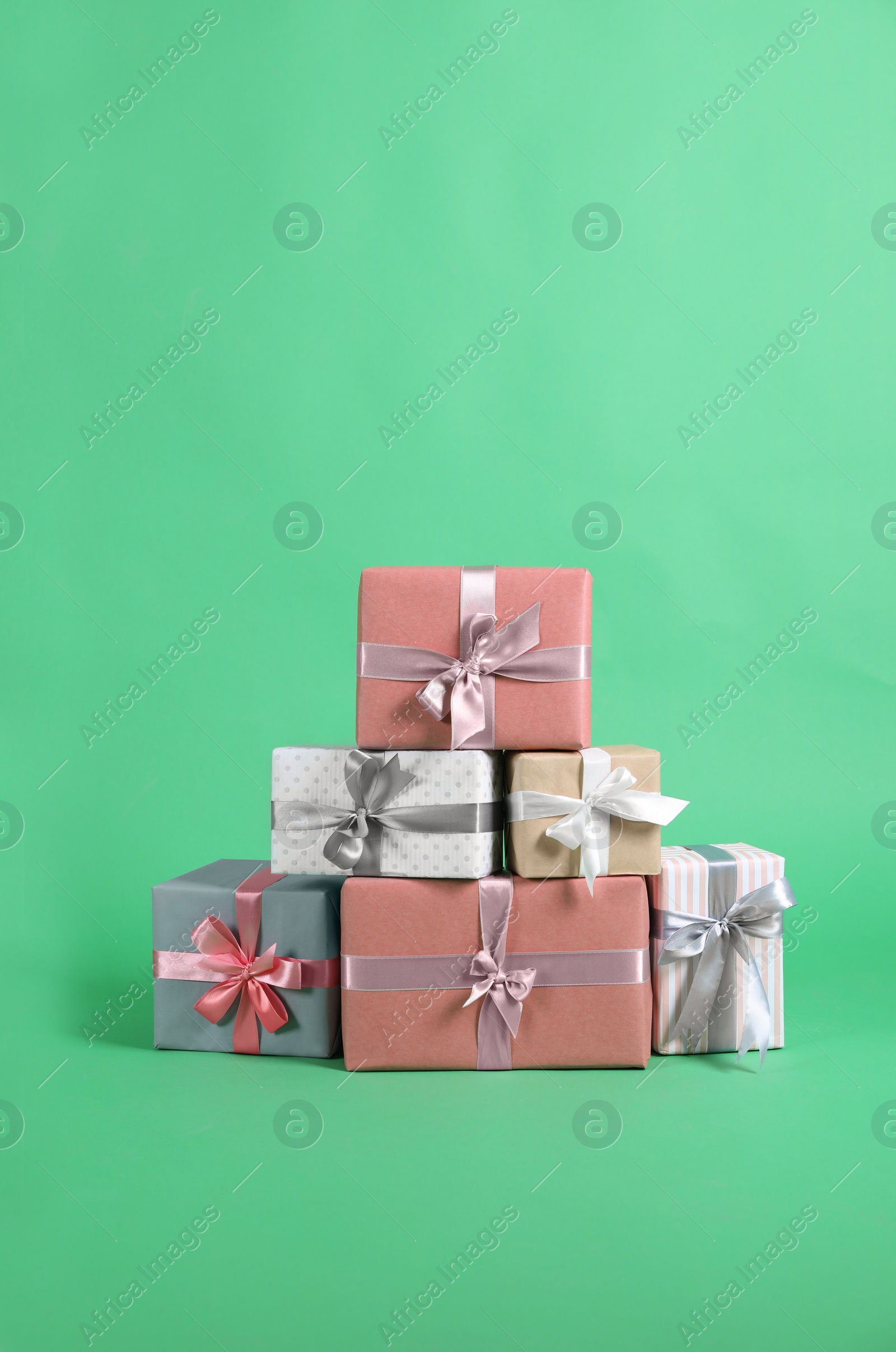 Photo of Many beautifully wrapped gift boxes on green background