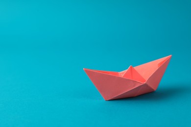 Handmade pink paper boat on light blue background.  Space for text