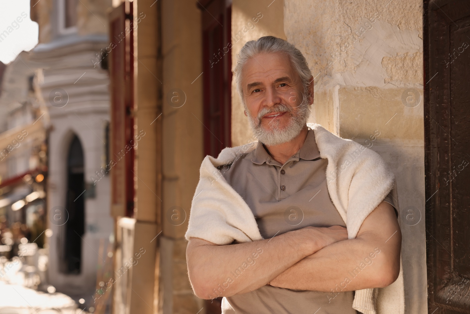 Photo of Handsome senior man standing near building outdoors, space for text