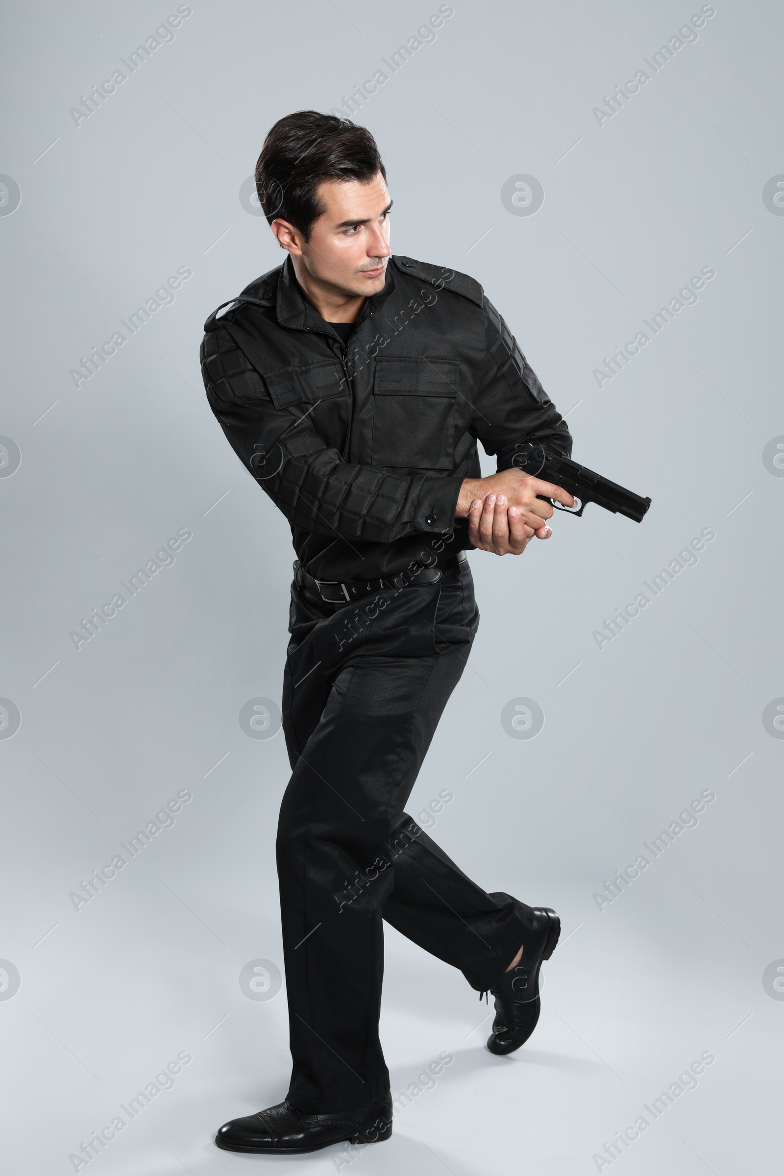 Photo of Male security guard in uniform with gun on grey background