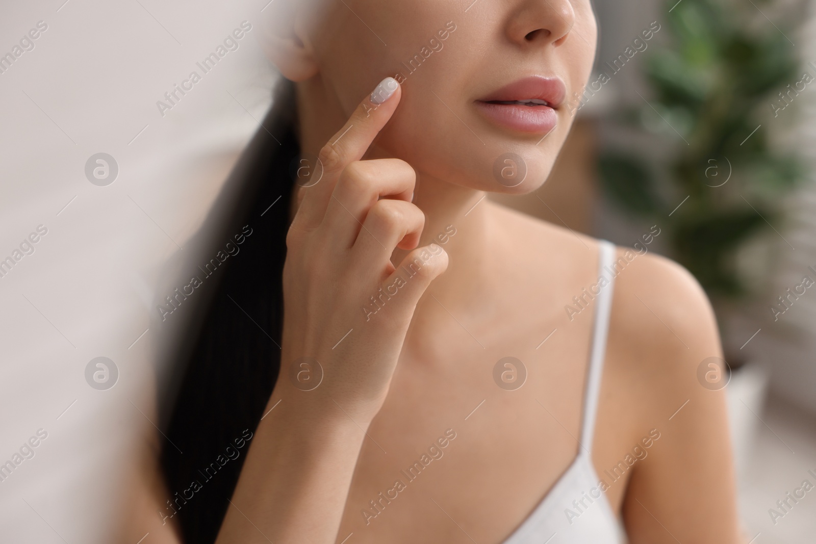 Photo of Woman with dry skin checking her face indoors, closeup