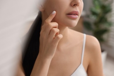 Woman with dry skin checking her face indoors, closeup