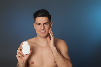 Photo of Handsome man holding post shave lotion on blue background
